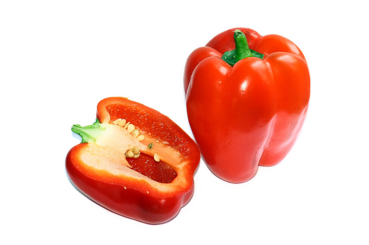 Красный толстостенный сладкий перец Capsicum annuum, целый плод и половинка в разрезе на белом фоне