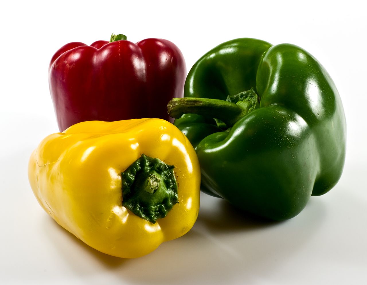 Красный, жёлтый и зелёный плоды сладкого перца Capsicum annuum на светлом фоне